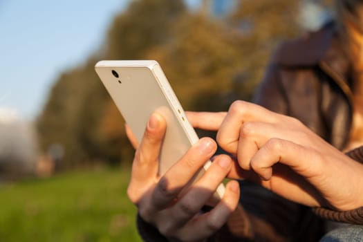 woman's hand holding smartphone in evening time