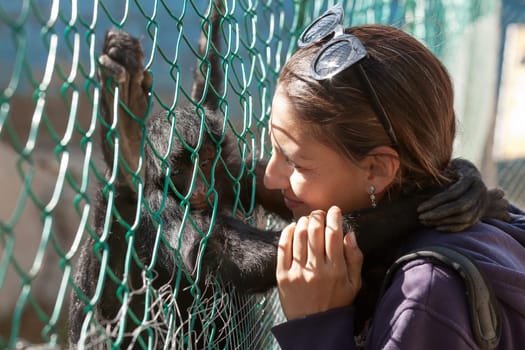 Portrait of a young woman playing and hugging spider monkey in ZOO