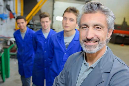 Smiling teacher with students stood behind him