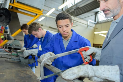 Apprentice learning to saw through a metal tube