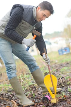 Man hammering a marker in the garden