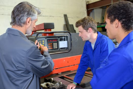 Man explaining workings of machine to two students