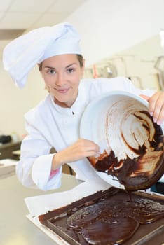 Chef scraping chocolate mixture into baking tray