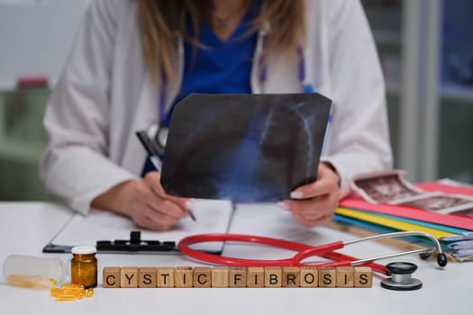 A healthcare professional carefully examines a cystic fibrosis Xray using medical tools while writing notes