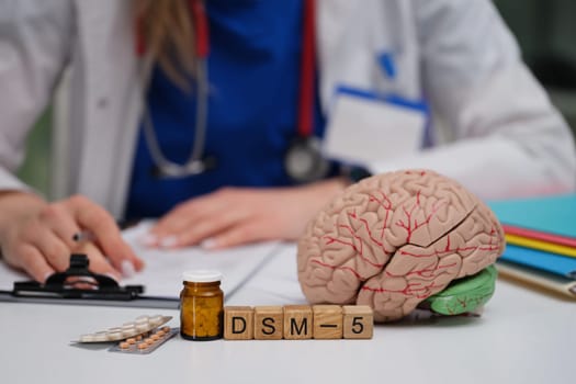 A workspace for a mental health professional showcasing a brain model along with the DSM5 for accurate diagnosis