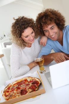 Couple eating pizza and websurfing on internet