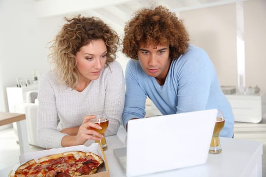 Couple eating pizza and websurfing on internet