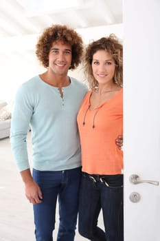 Cheerful couple opening new home entrance door