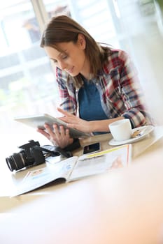 Young woman in coffee shop working on tablet