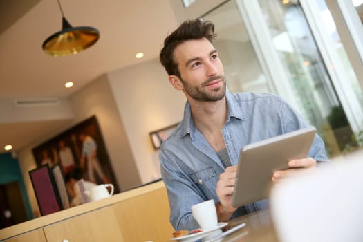 Man websurfing on digital tablet in coffee shop