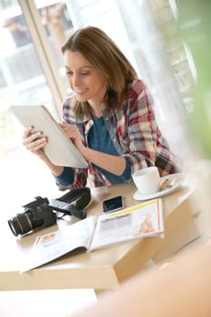 Young woman in coffee shop working on tablet