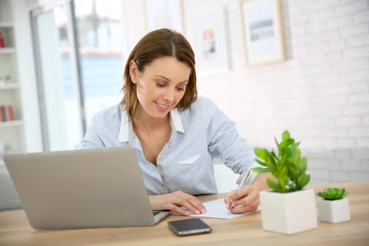 Woman in office writing on paper