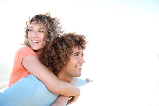 Man giving piggyback ride to girlfriend on the beach