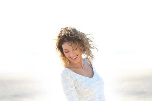 Beautiful smiling blond woman standing on a beach