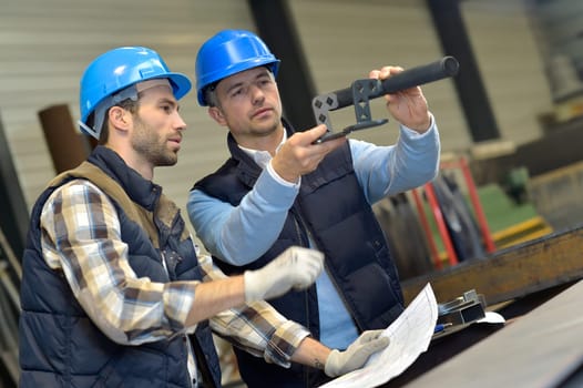 Engineer with mechanical worker checking on production