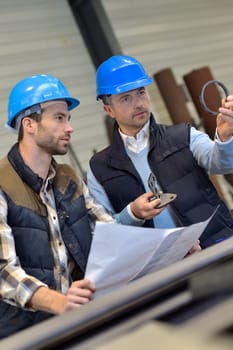 Engineer with mechanical worker checking on production