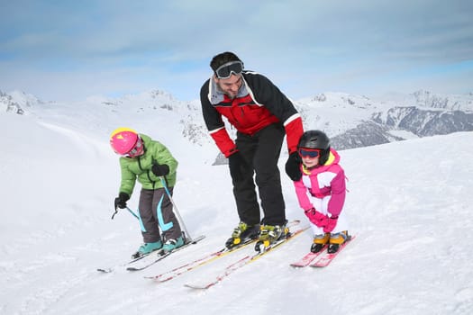 Ski instructor teaching young kids to go down ski slope