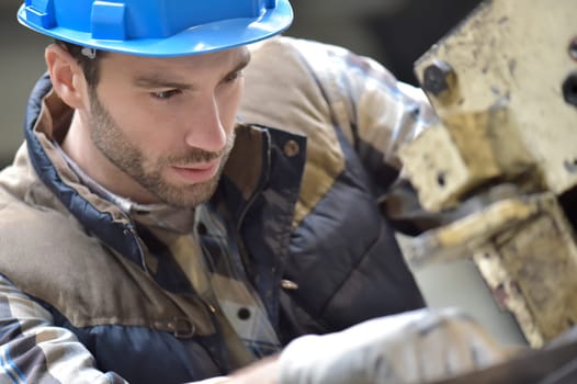 Industrial worker working on machine in factory