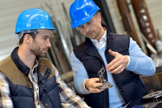 Engineer with mechanical worker checking on production
