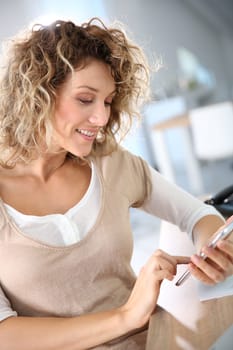 Woman in office sending message with smartphone