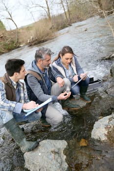 Biologist with students in science testing river water