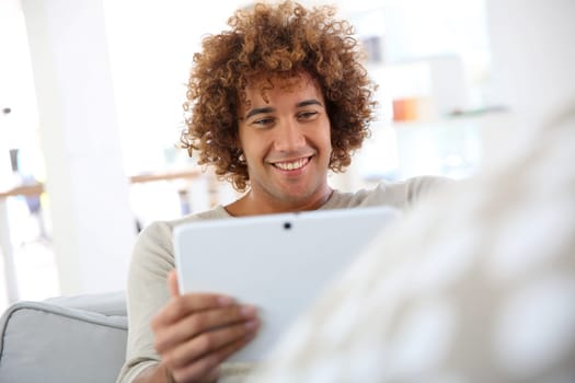 Cheerful mixed-raced guy websurfing on tablet