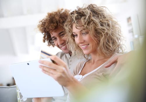 Cheerful couple at home e-shopping with tablet