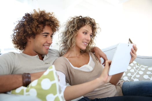 Cheerful couple at home e-shopping with tablet