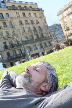 Mature man having a nap in city park