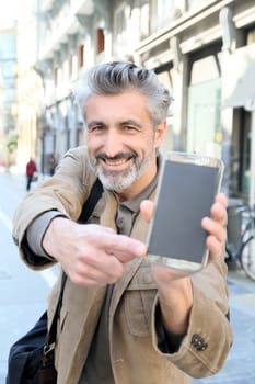 Cheerful mature man showing smartphone to camera
