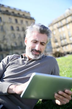 Man connected on tablet in public park