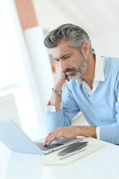 Trendy mature man working from home with laptop