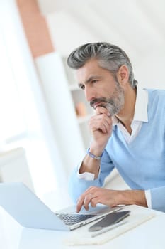 Trendy mature man working from home with laptop