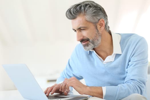 Trendy mature man working from home with laptop