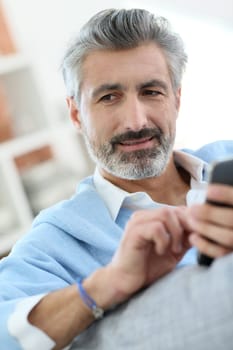 Mature man sending message with smartphone