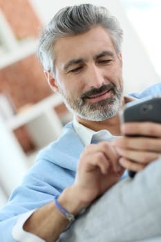 Mature man sending message with smartphone