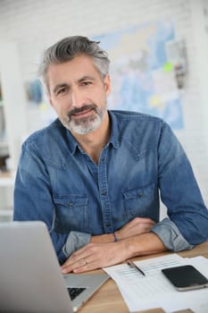 Mature man working on laptop in school office