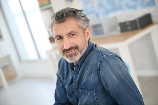 Smiling teacher sitting at desk in university office