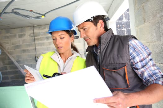 Engineers on building site checking plans