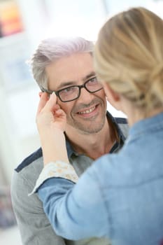 Mature man in optical store trying eyeglasses on