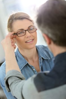 Mature blond woman with optician trying eyeglasses