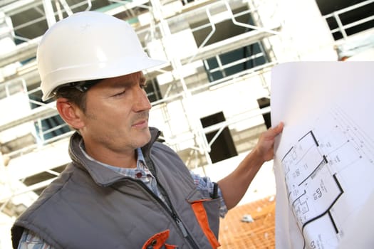 Construction manager on building site holding blueprint