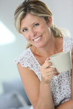 Relaxed woman having hot tea at home