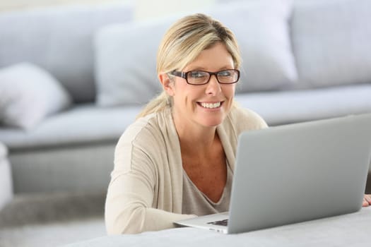 Mature woman with eyeglasses websurfing on laptop