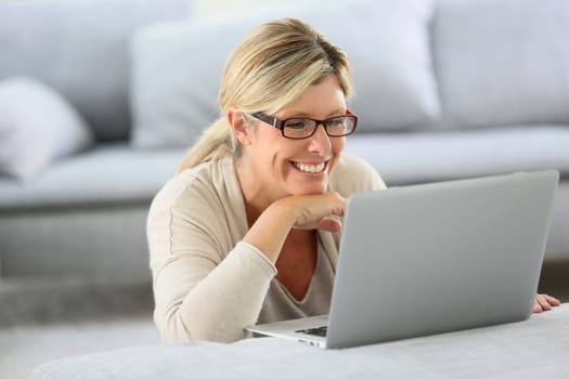 Mature woman with eyeglasses websurfing on laptop