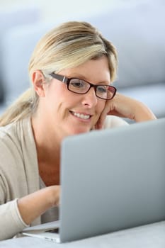 Mature woman with eyeglasses websurfing on laptop
