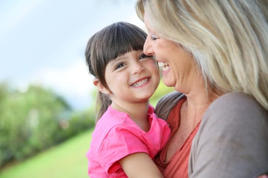 Cheerful woman embracing little girl in arms