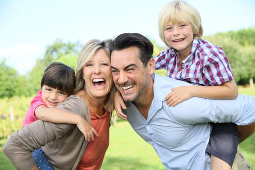 Parents giving piggyback ride to kids in park