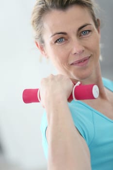 Portrait of mature fitness woman lifting dumbbells