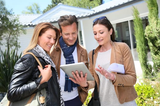 Real-estate agent with tablet showing house to clients